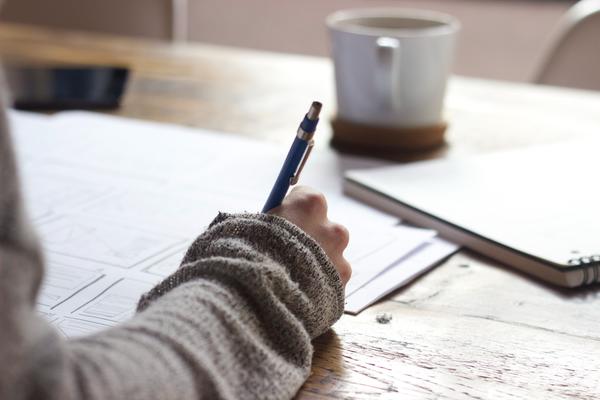 close up of female writing with coffee cup in background